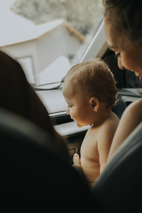 Mẹ đang nhẹ nhàng an ủi bé khi ngồi trên ghế an toàn trẻ em trên ô tô